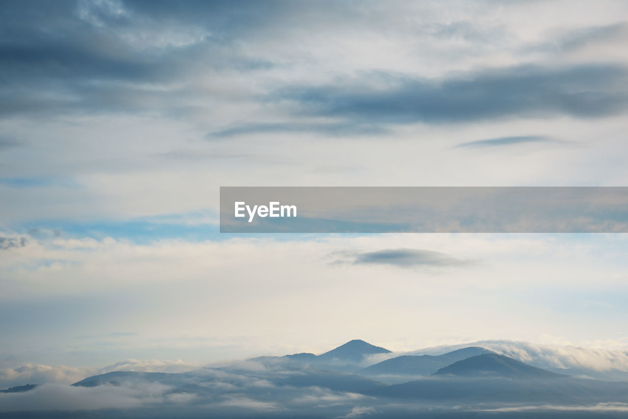 Scenery of clouds around mountain range and overcast sky