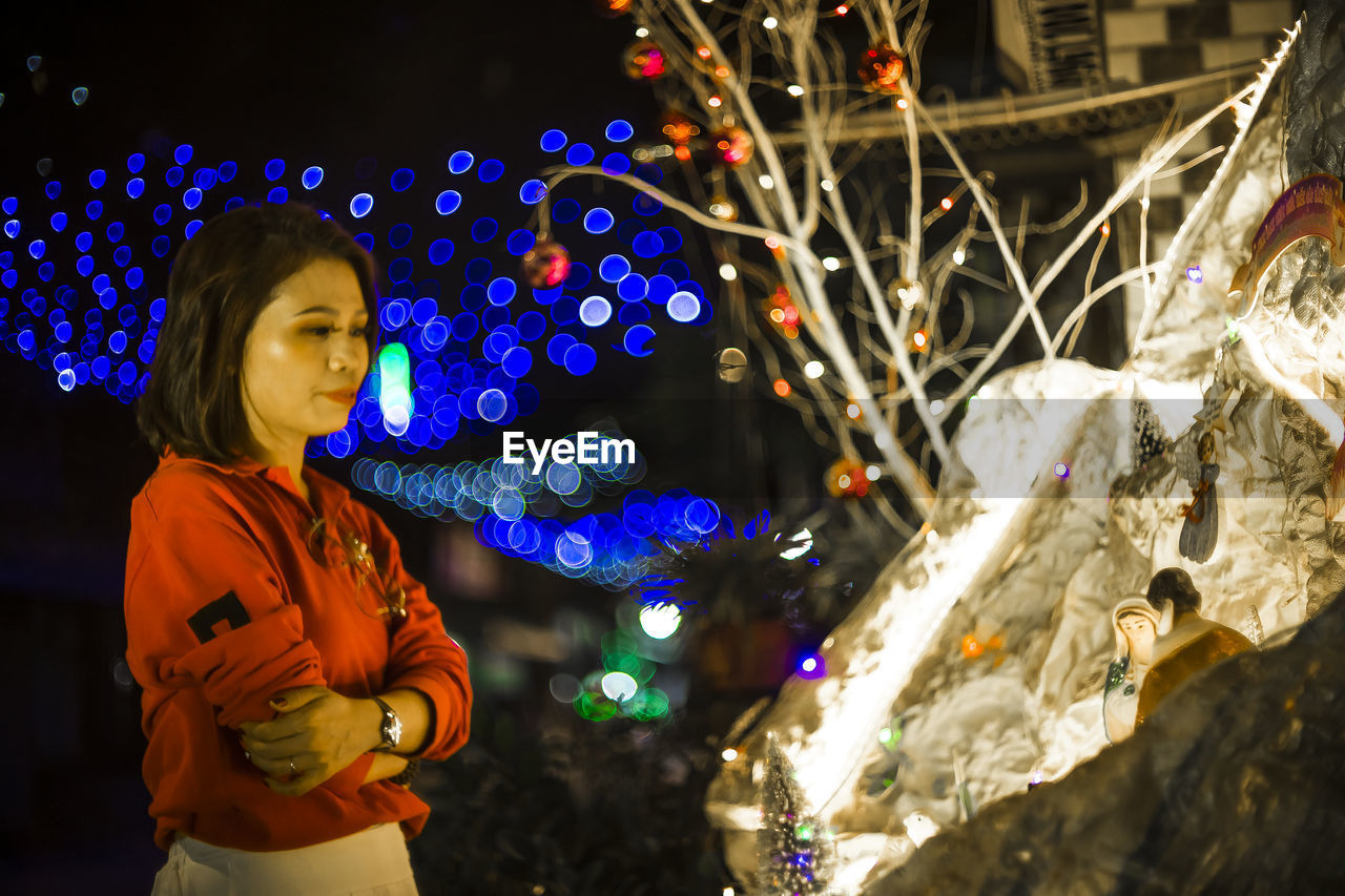 one person, night, illuminated, christmas lights, decoration, christmas decoration, celebration, holiday, women, christmas, nature, adult, standing, child, looking, outdoors, childhood, person, tree, christmas tree, clothing, waist up, multi colored, tradition, young adult, three quarter length