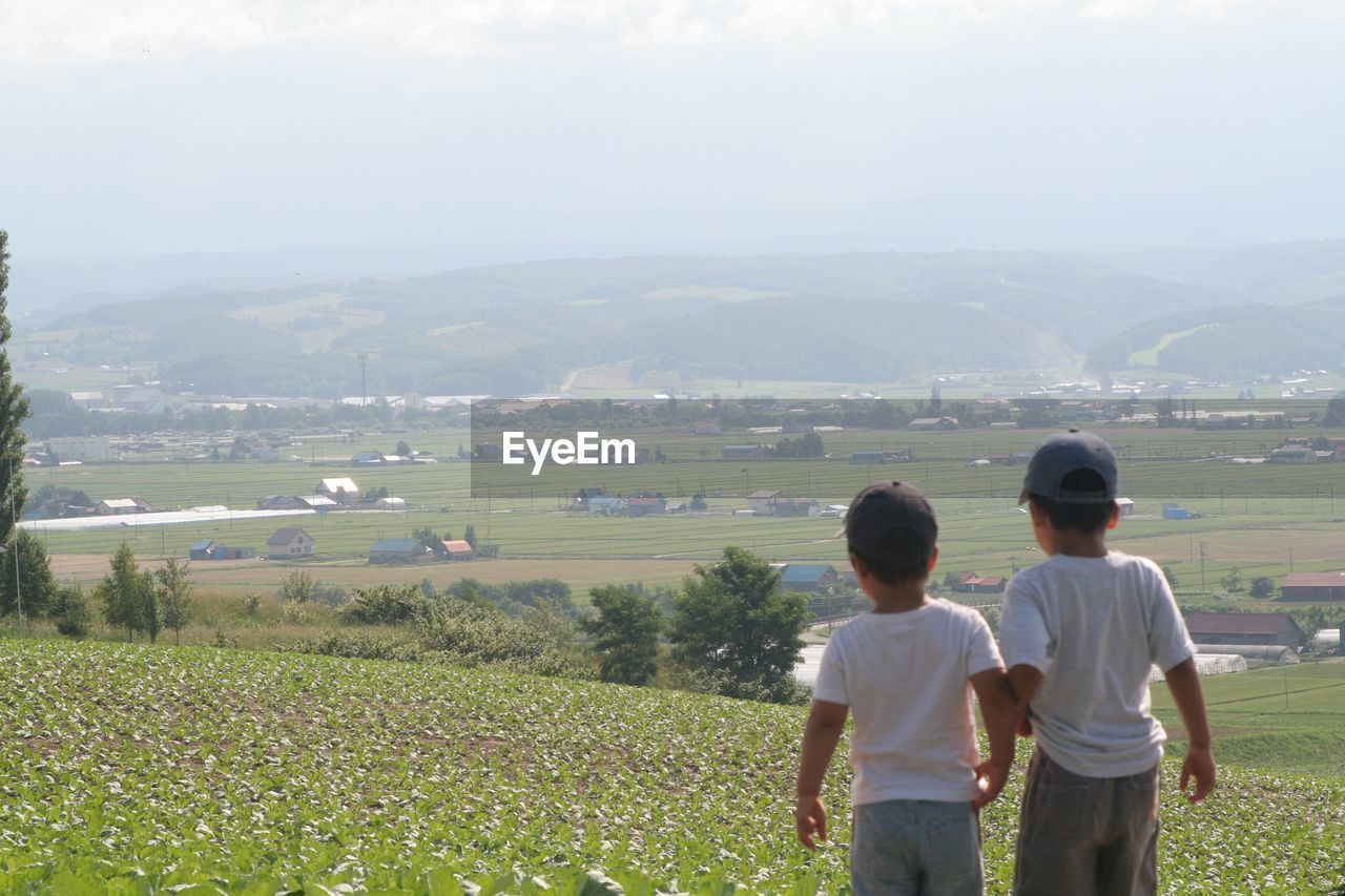 Rear view of siblings standing on field