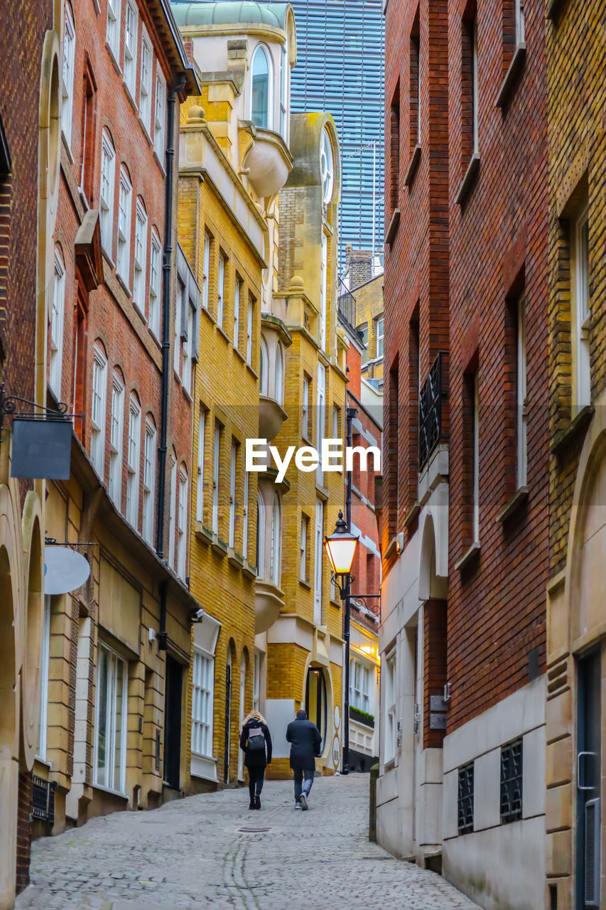 PEOPLE WALKING ON STREET AMIDST BUILDINGS