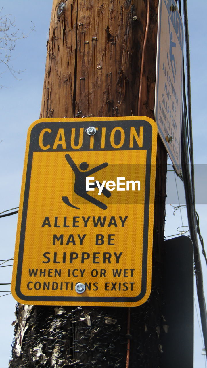 Close-up of warning sign mounted on wooden pole