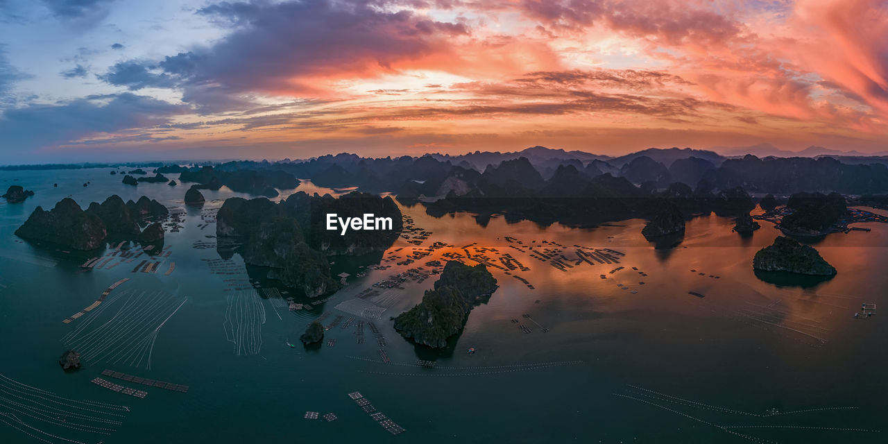 Scenic view of lake against cloudy sky during sunset