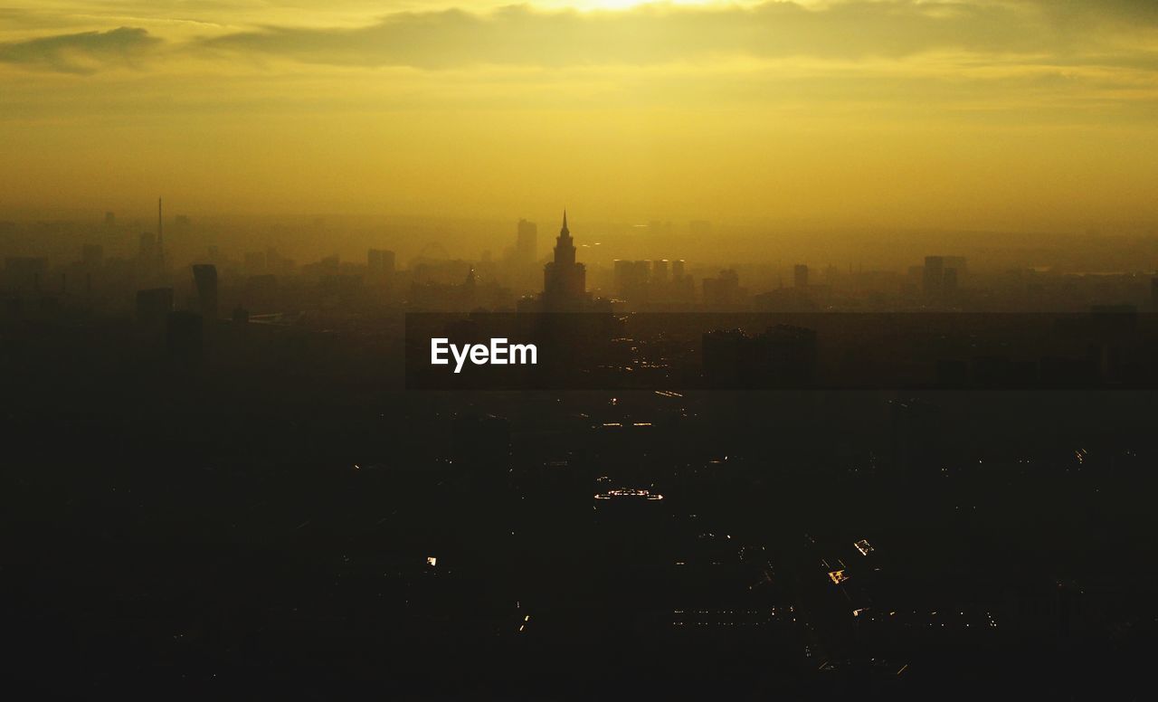 Silhouette of buildings in city at sunset