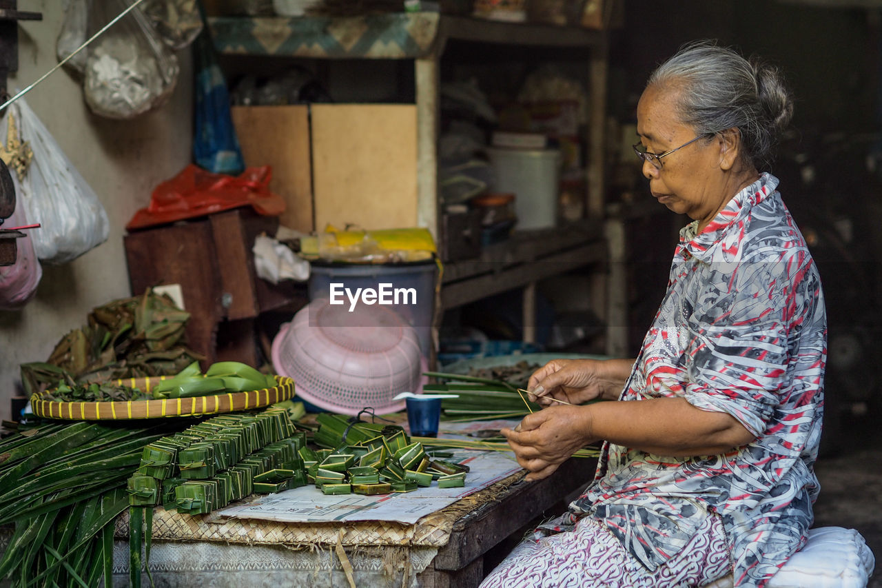 Side view of woman wrapping leaves on table