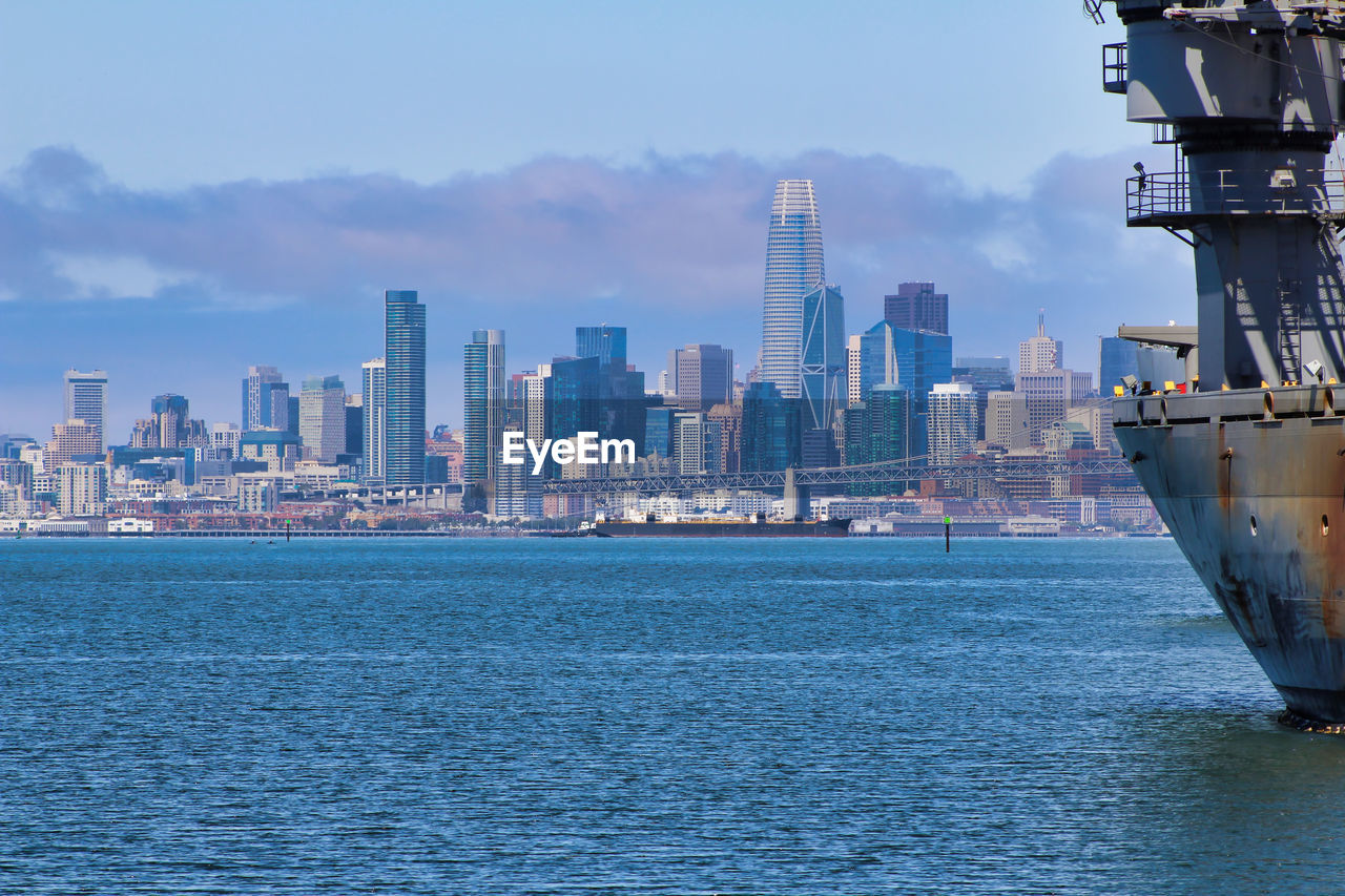 SEA BY CITY BUILDINGS AGAINST SKY