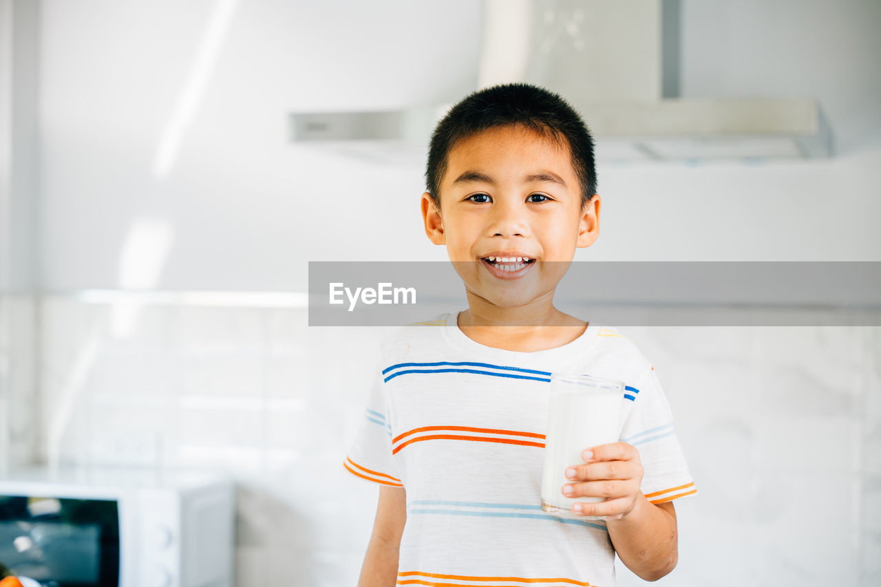 portrait of boy standing against wall at home