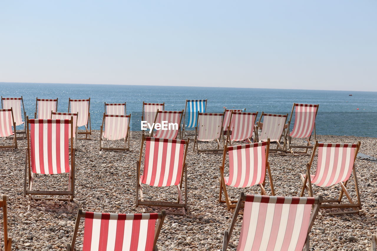 DECK CHAIRS ON BEACH AGAINST SKY