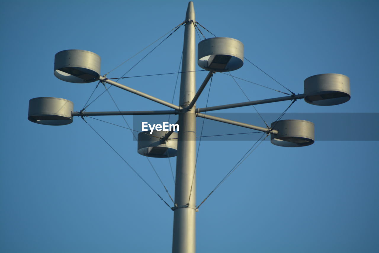 Low angle view of electricity pylon against blue sky