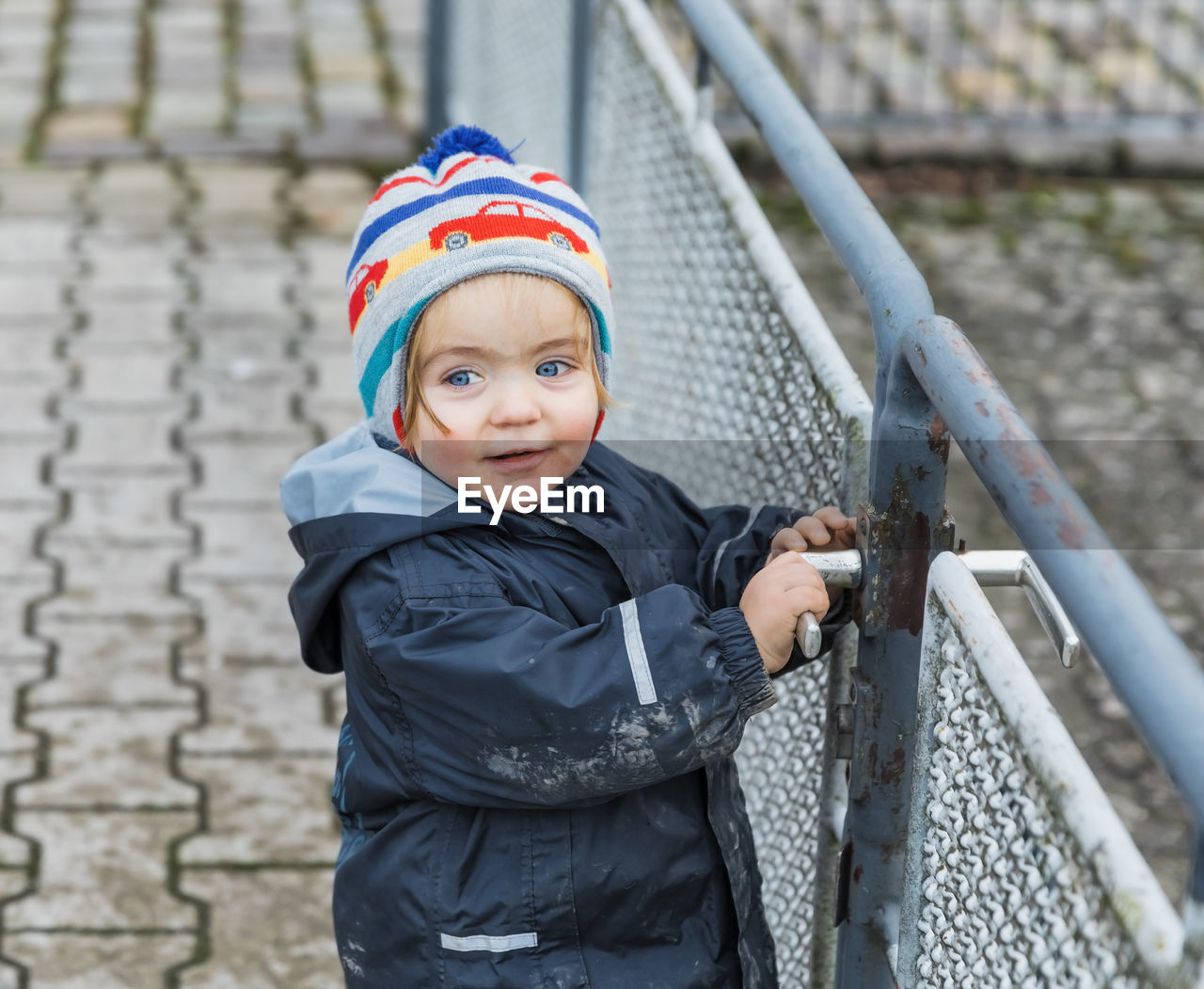 Cute girl in warm clothes standing by railing