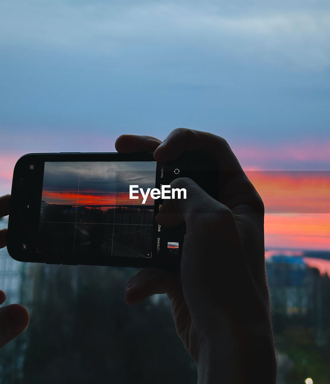 one person, sky, hand, holding, technology, photographing, light, wireless technology, communication, activity, cloud, smartphone, portable information device, sunset, adult, camera, nature, outdoors, focus on foreground, mobile phone, lifestyles, close-up, leisure activity, blue, selfie, screen
