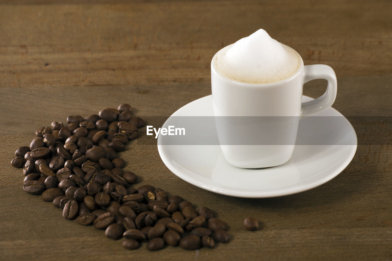 CLOSE-UP OF COFFEE CUP WITH COOKIES ON TABLE