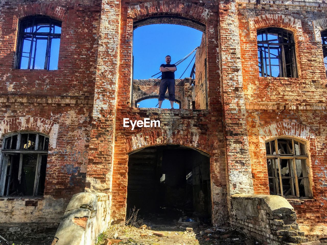 MAN STANDING BY OLD BUILDING
