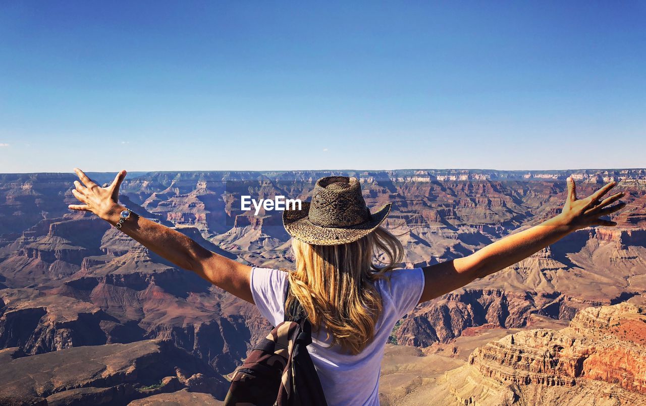 Rear view of woman standing on landscape against clear sky