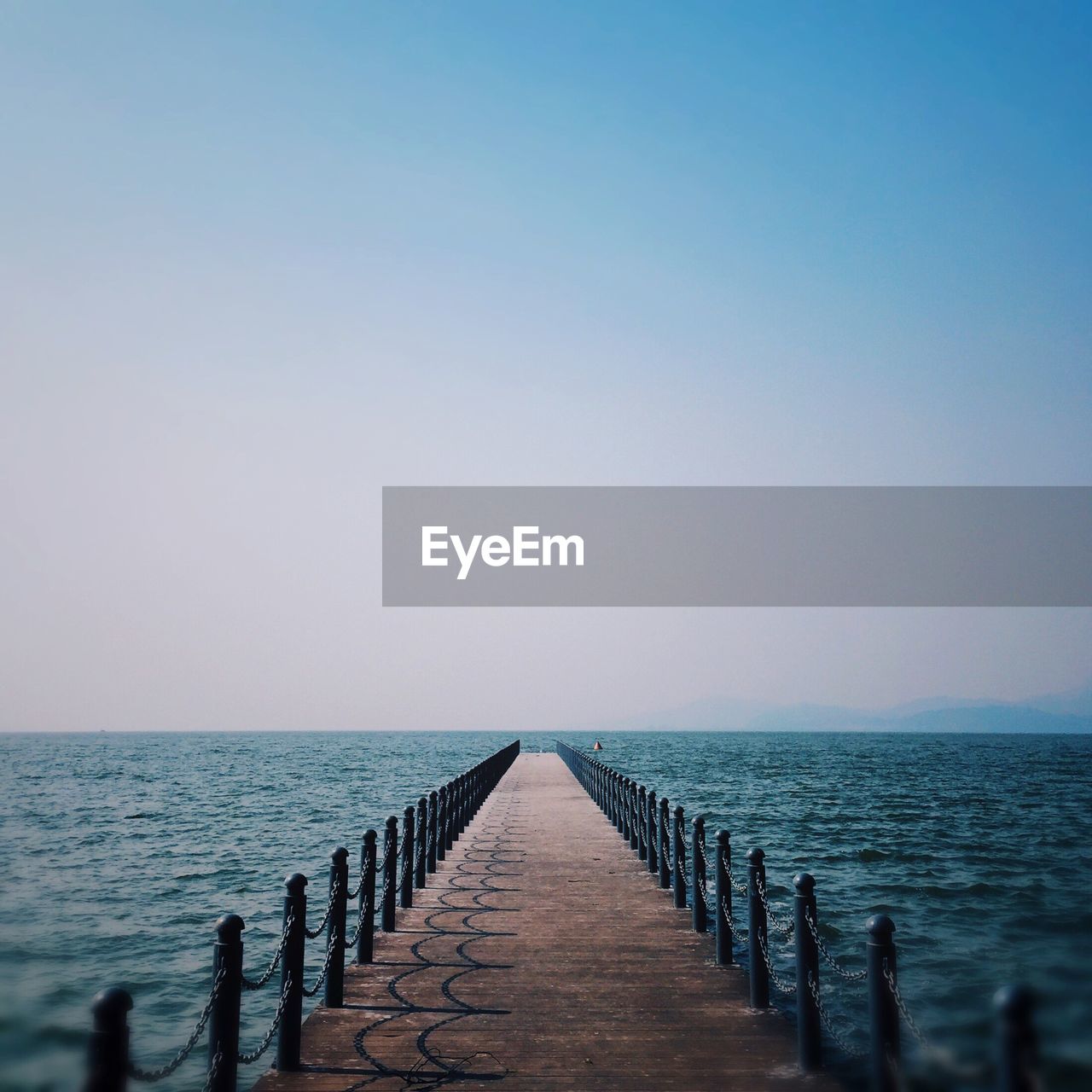 Wooden pier in sea against clear sky