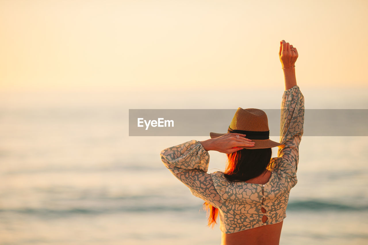 rear view of woman standing at beach