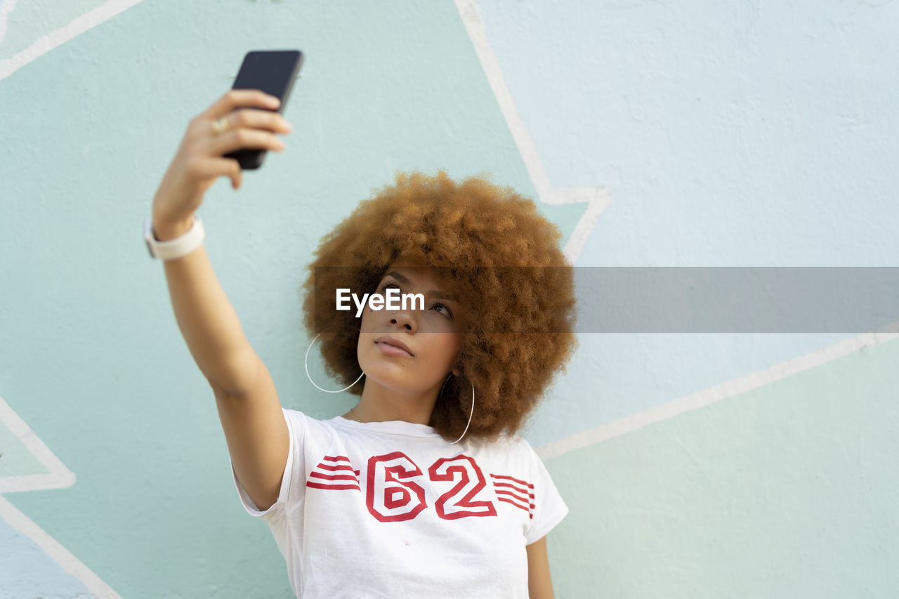 Woman with afro hair taking a selfie with her smartphone