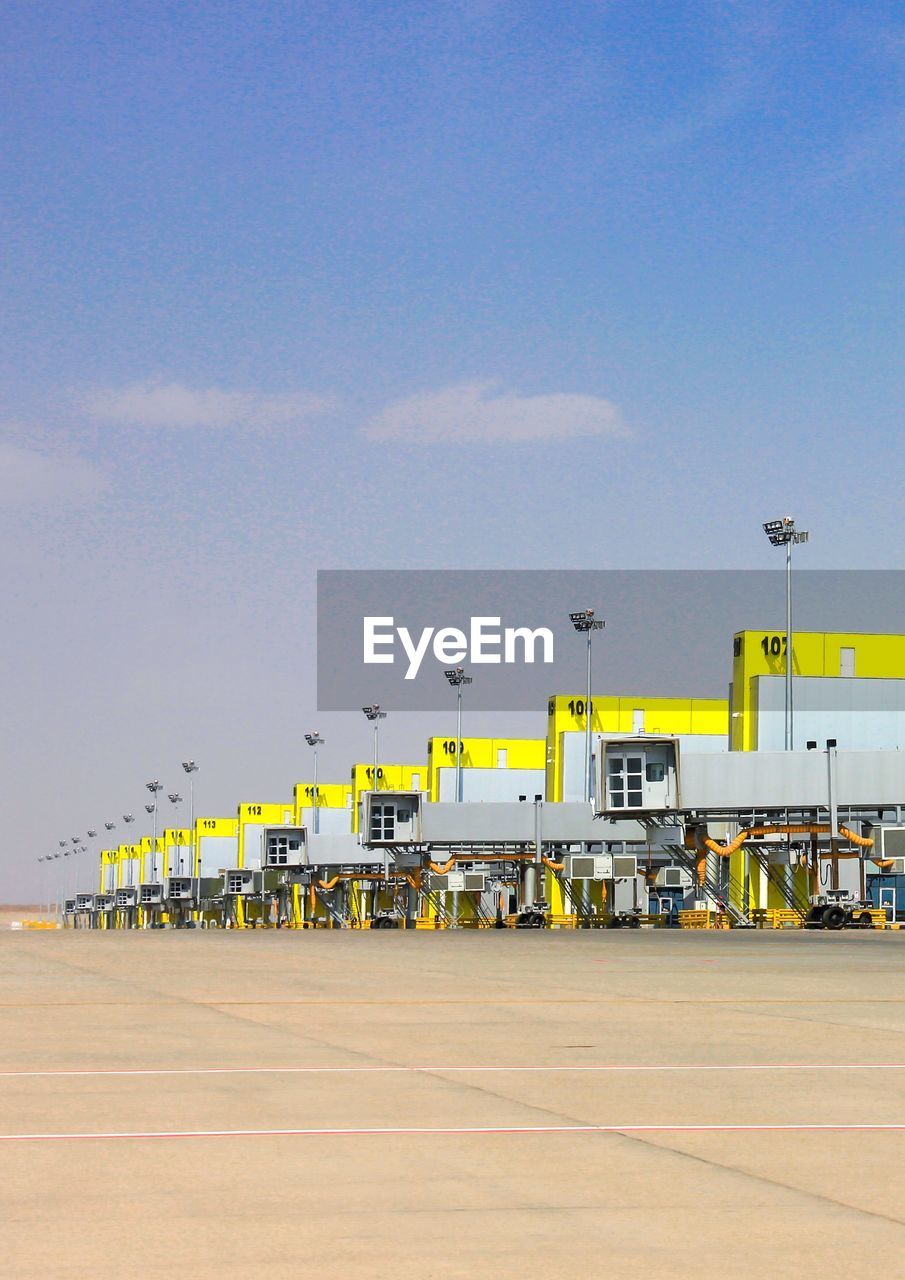 Row of boarding bridges at prince mohammad airport against sky