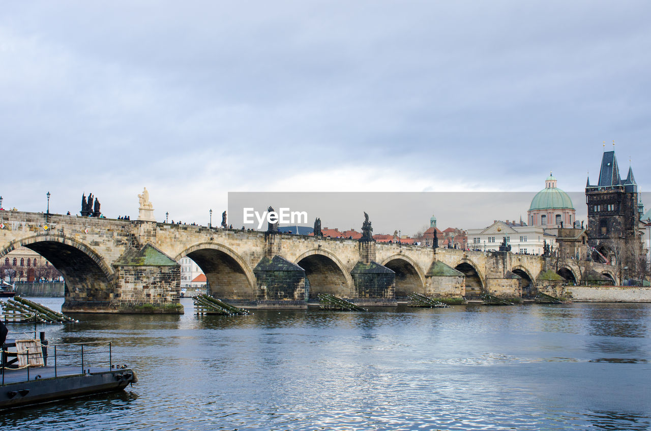 Bridge over river against cloudy sky