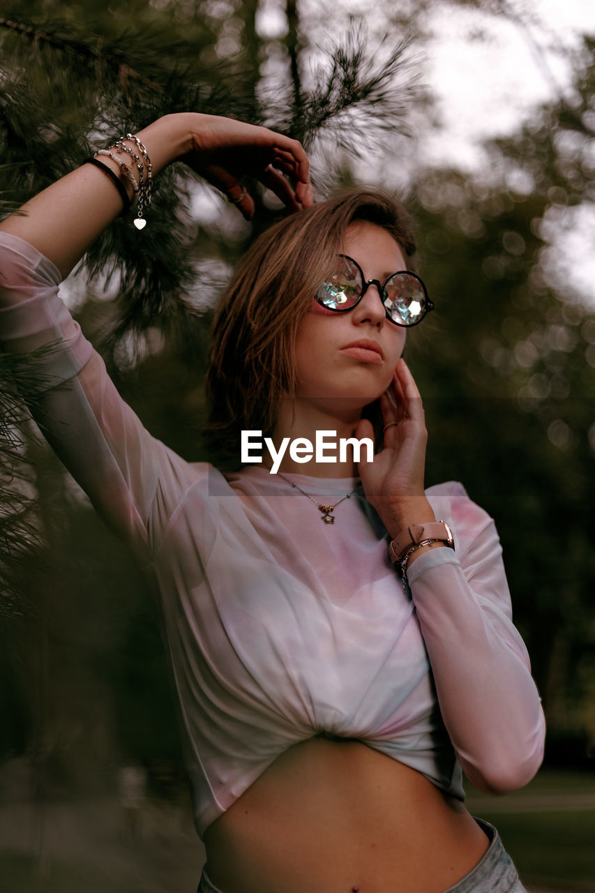 Beautiful young woman wearing eyeglasses against trees