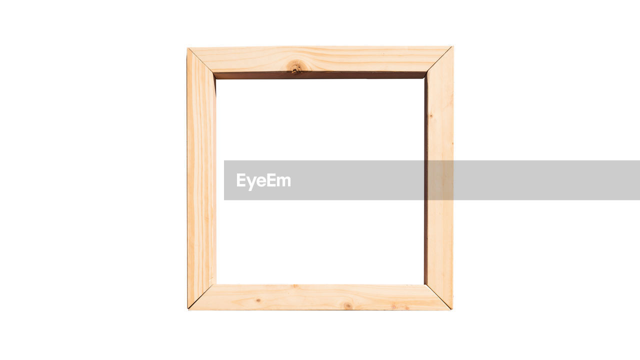 Low angle view of empty wooden frame hanging against white wall