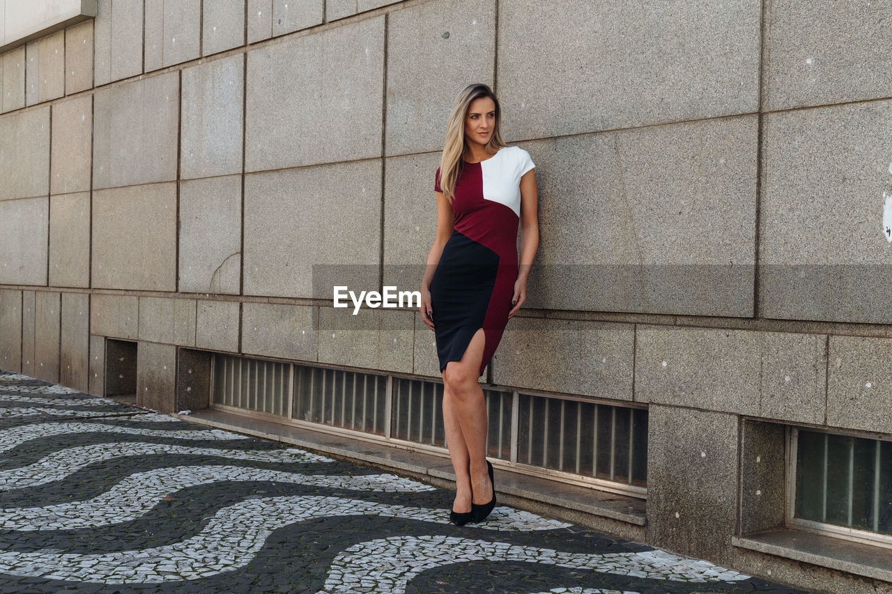 Woman looking away while standing against building