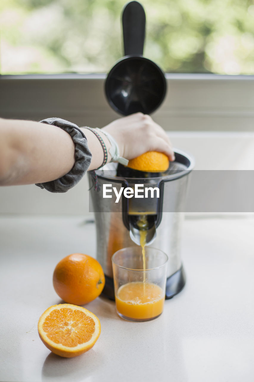 Midsection of man preparing orange juice