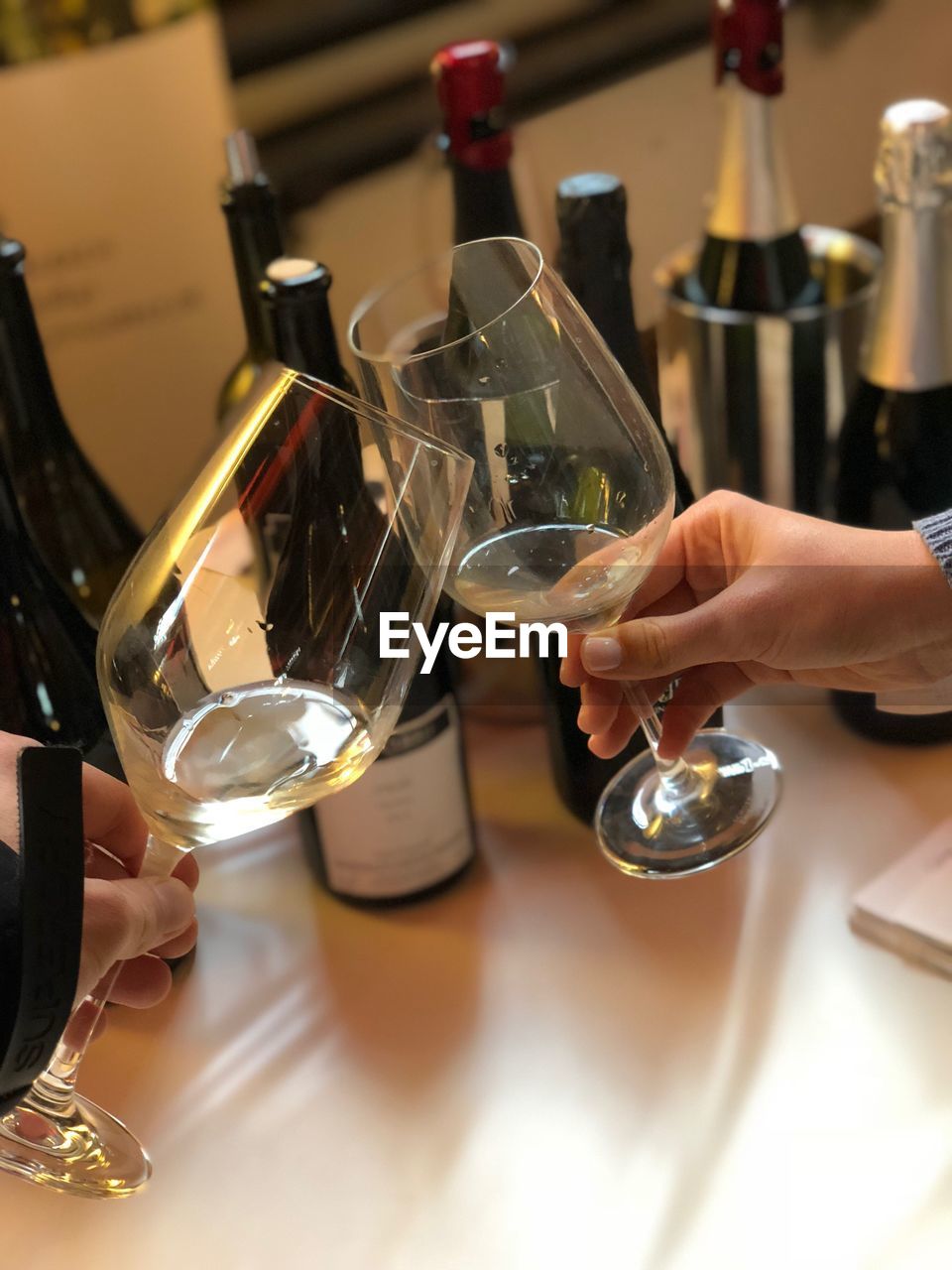 MIDSECTION OF WOMAN HOLDING WINE GLASSES ON TABLE AT RESTAURANT