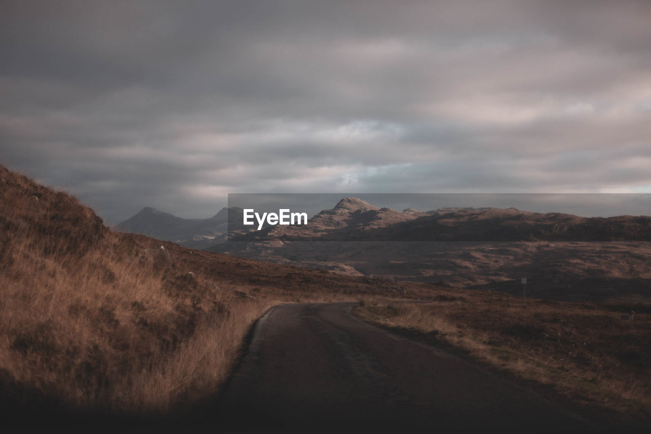 Road leading towards mountains against sky