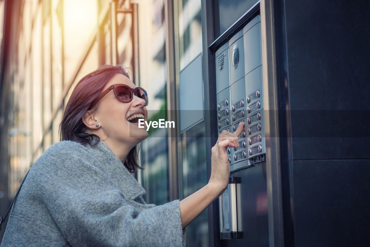 Smiling woman using intercom in city