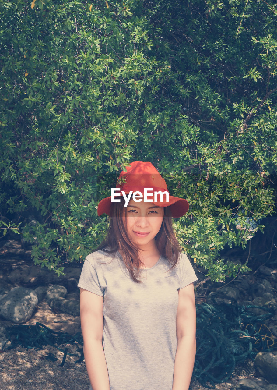 Portrait of smiling young woman standing against plants