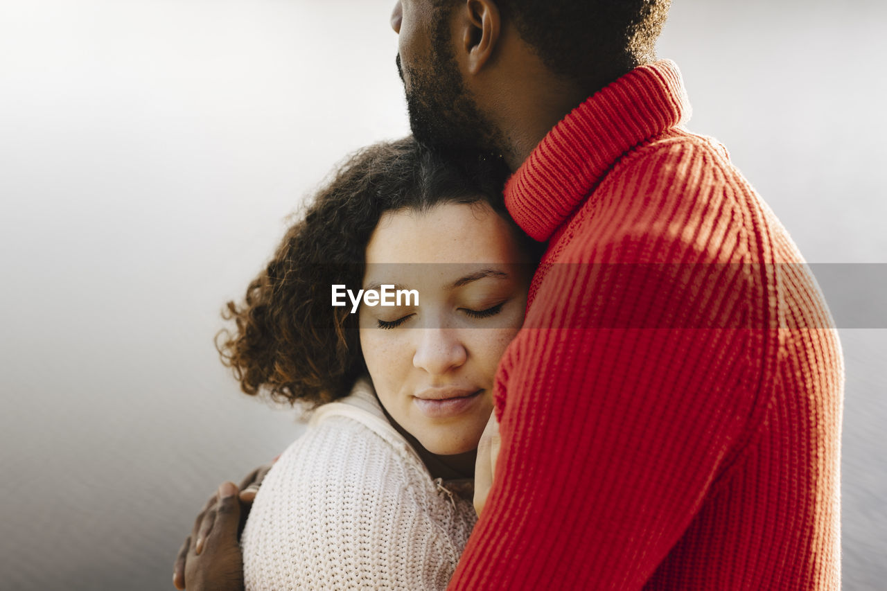 Young woman with eyes closed embracing boyfriend