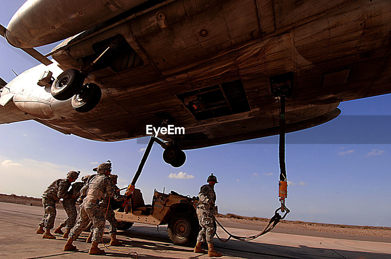 LOW ANGLE VIEW OF PEOPLE AT AIRPLANE