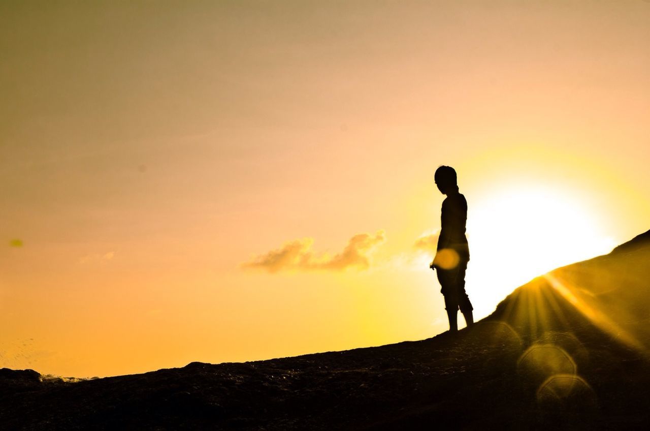 Silhouette woman standing against sky at sunset