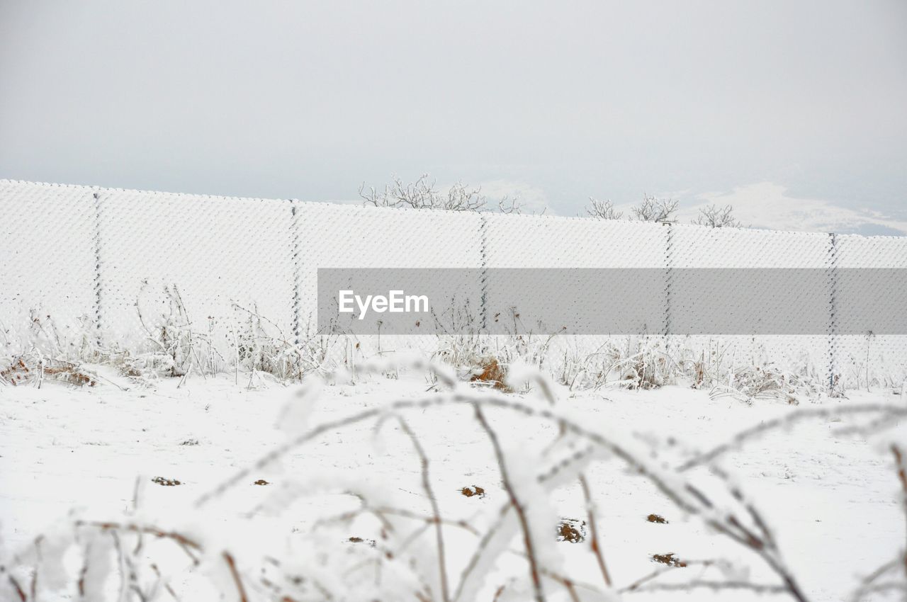 Snow covered chainlink fence on landscape