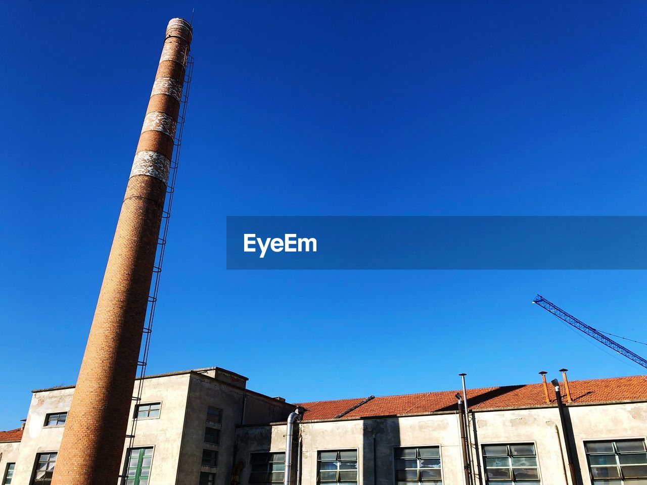 LOW ANGLE VIEW OF SMOKE STACKS AGAINST CLEAR BLUE SKY