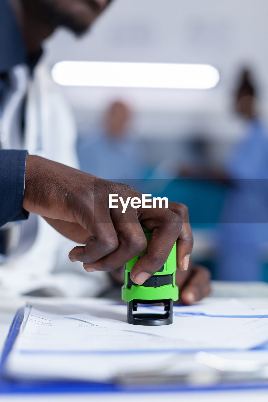 midsection of man using mobile phone at table