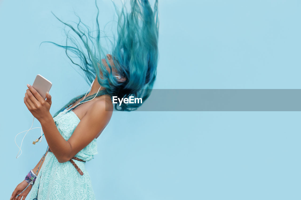 Midsection of woman drinking water against blue background