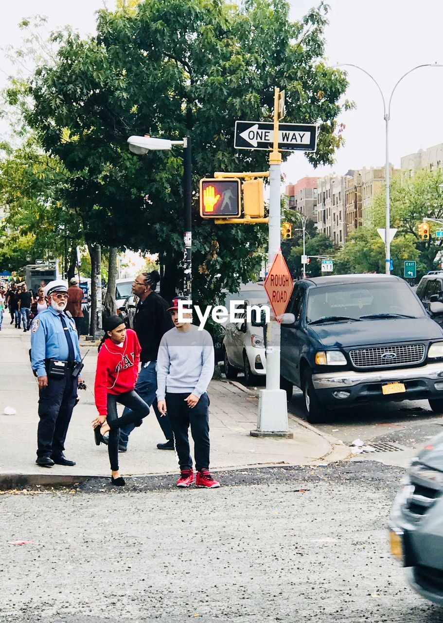 REAR VIEW OF PEOPLE WALKING ON ROAD