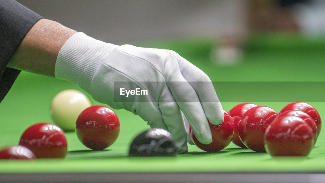 Cropped hand of man adjusting snooker balls on pool table