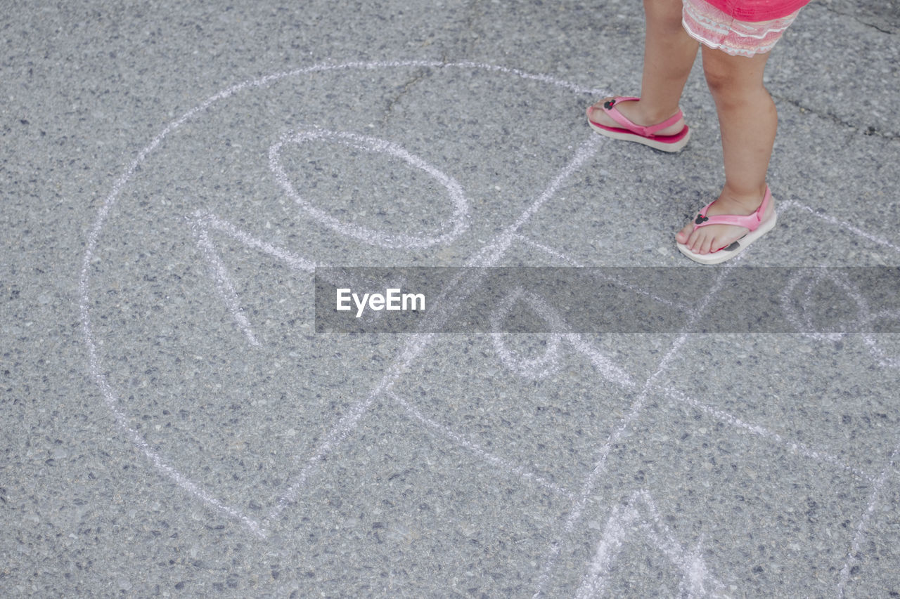 Low section of girl playing hopscotch on street