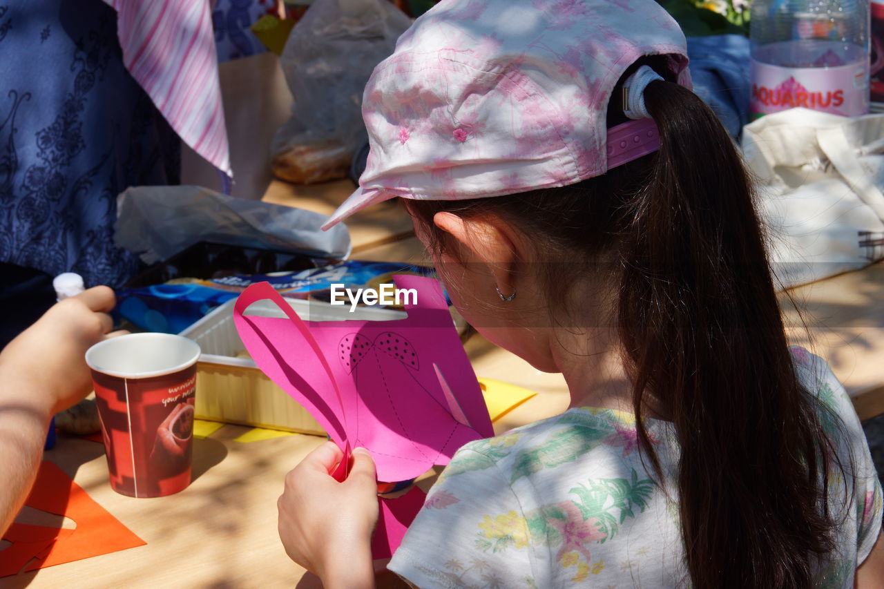 Close-up of girl cutting paper in sunny day