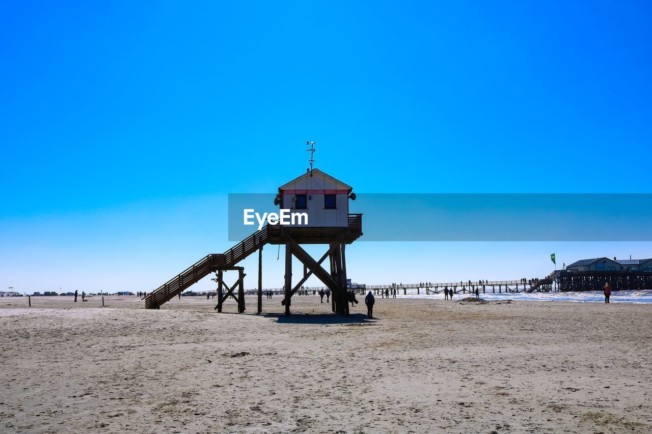 Lifeguard hut on beach against blue sky