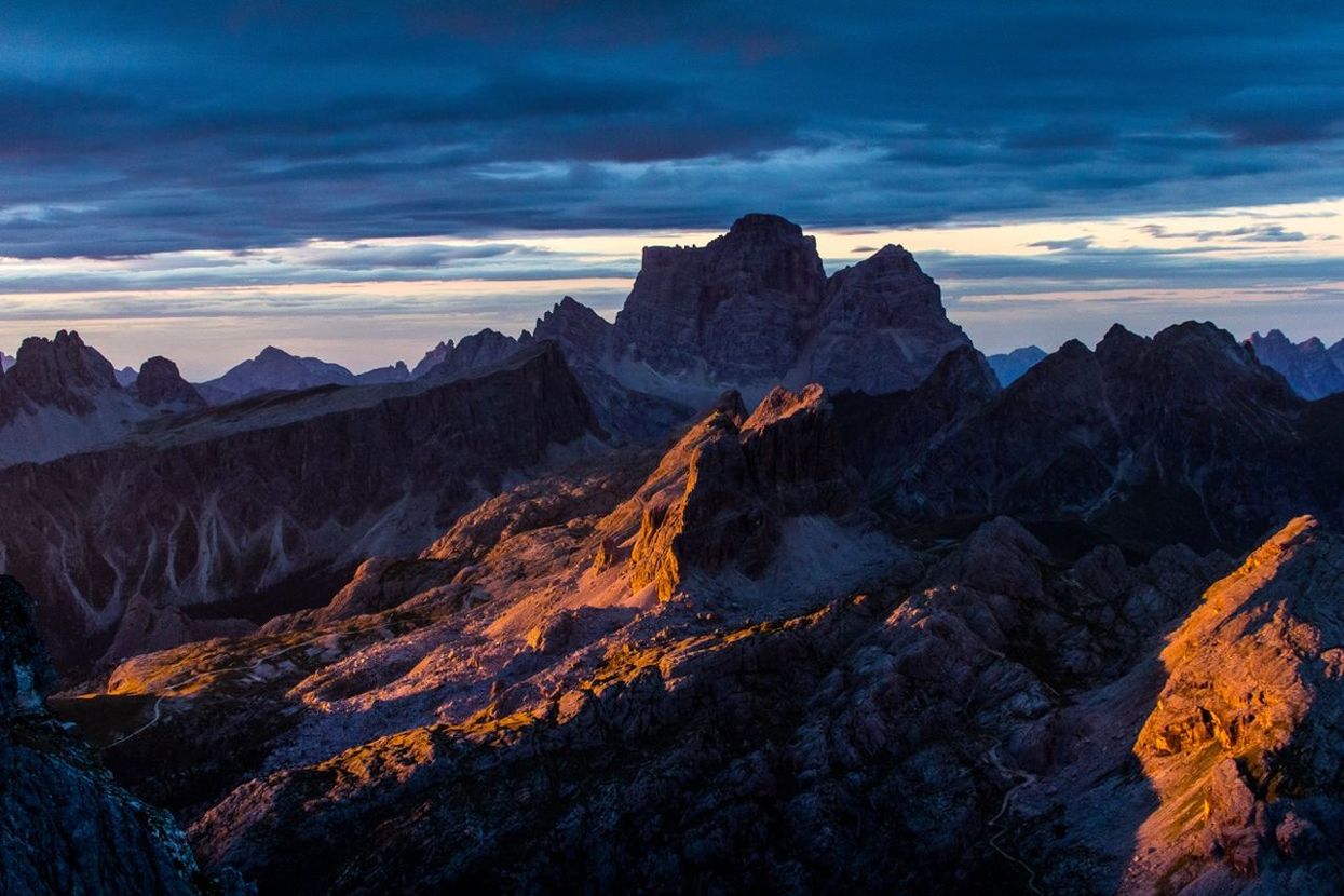 Scenic view of rocky mountains against cloudy sky during sunset