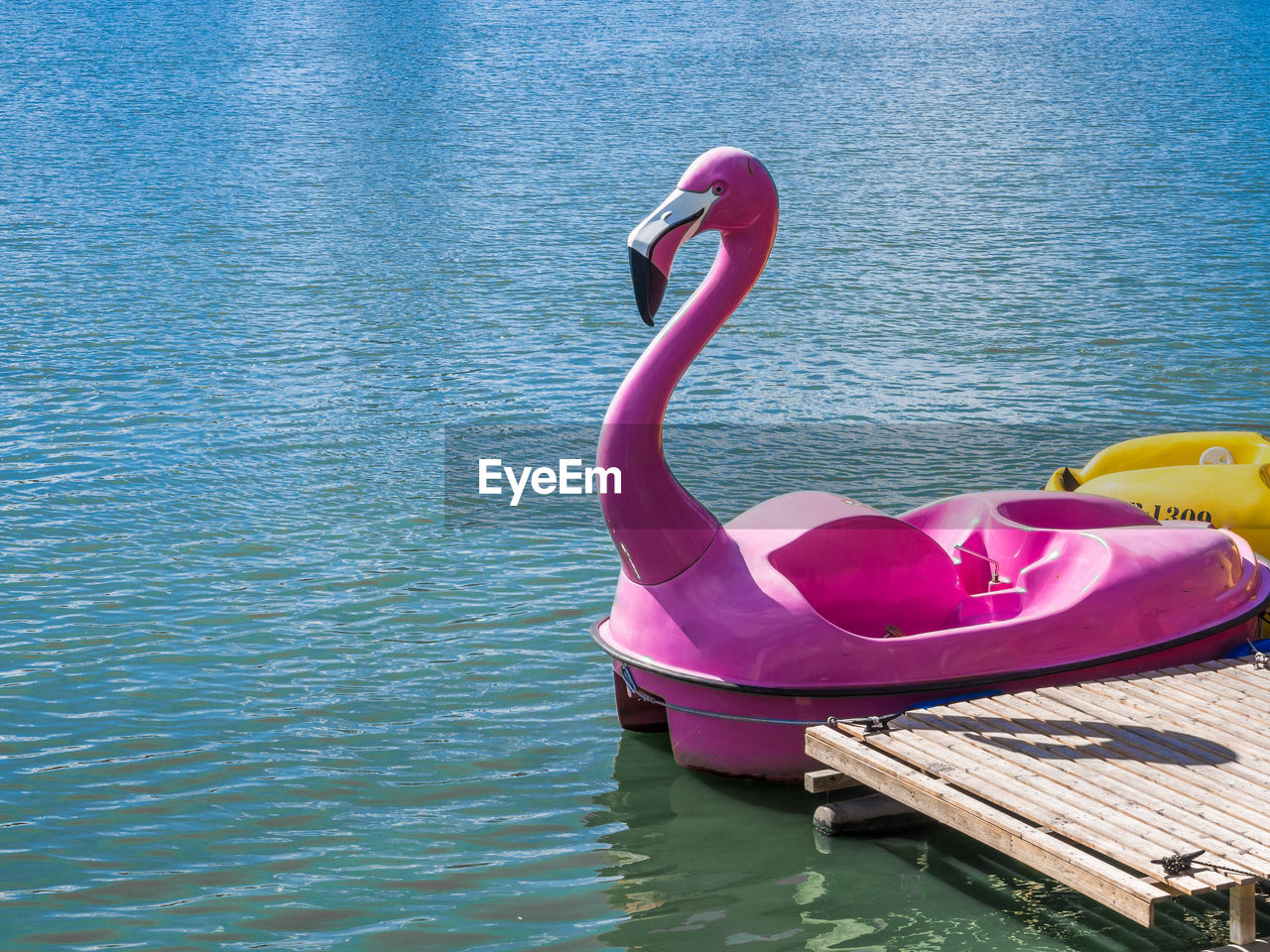 Pink flamingo pedal boat floating on water in lake