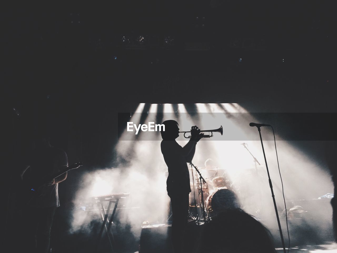 Silhouette man playing trumpet with performer in smoke