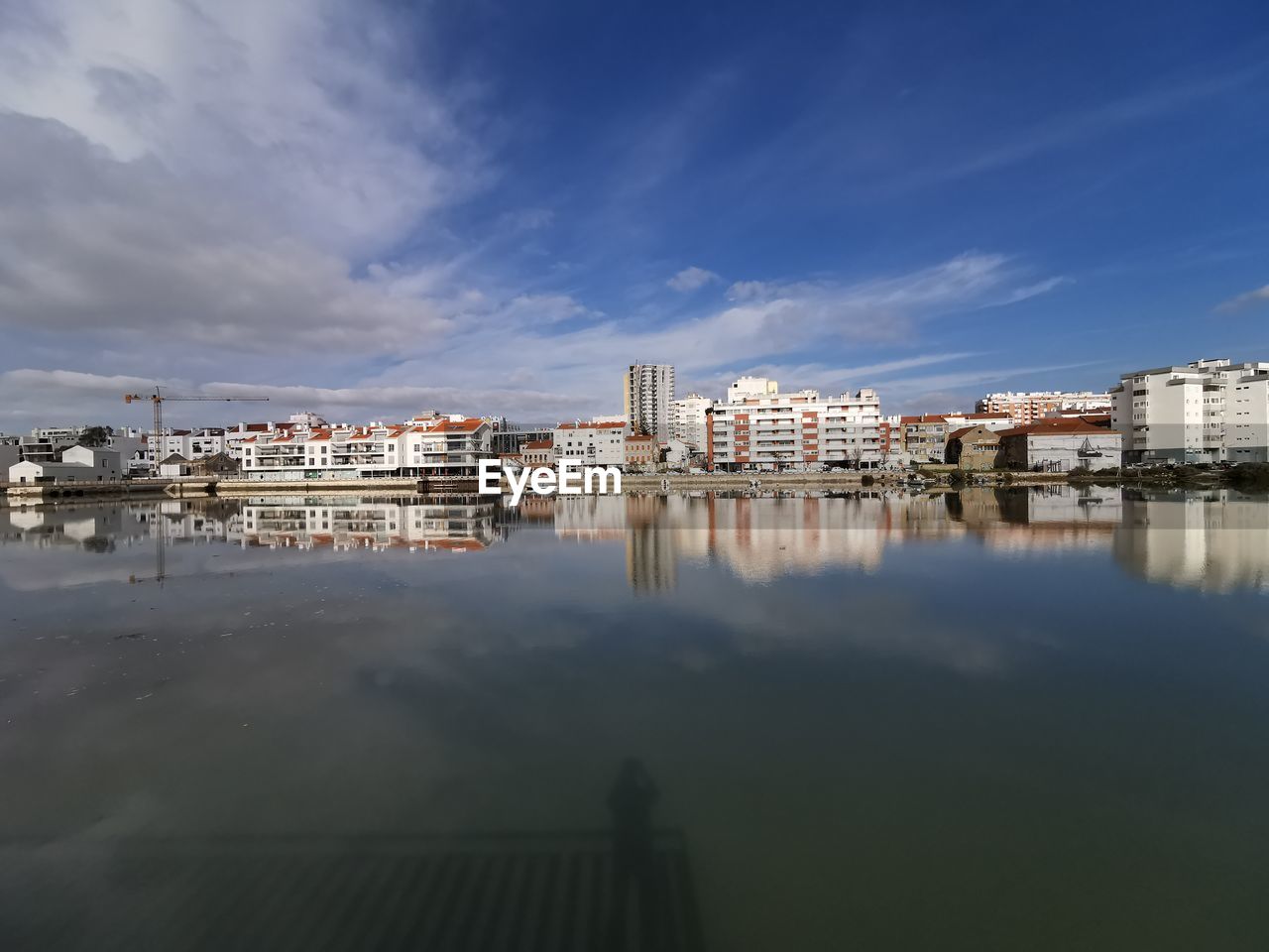 Reflection of buildings in sea against sky