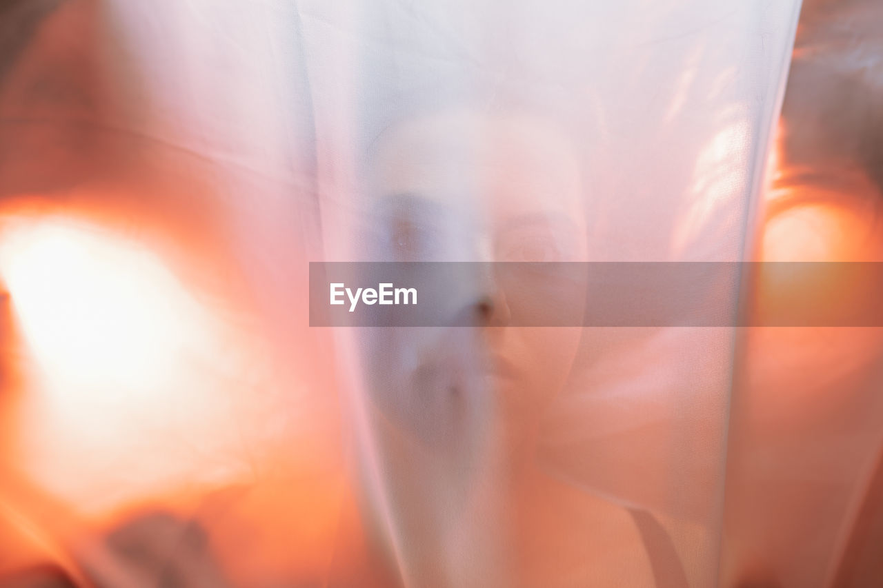 Close-up of woman standing behind orange cloth