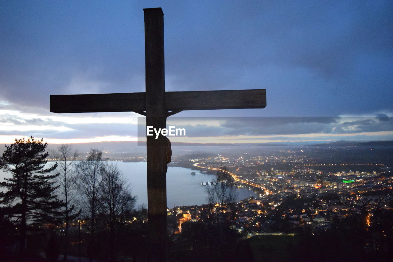 Rear view of cross overlooking city by sea