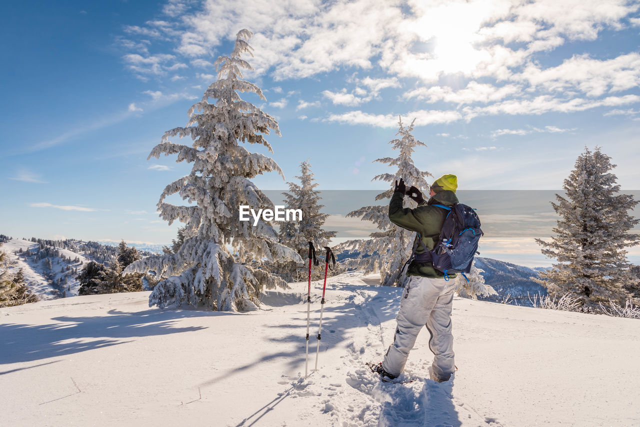 Rear view of man on snow covered mountain against sky