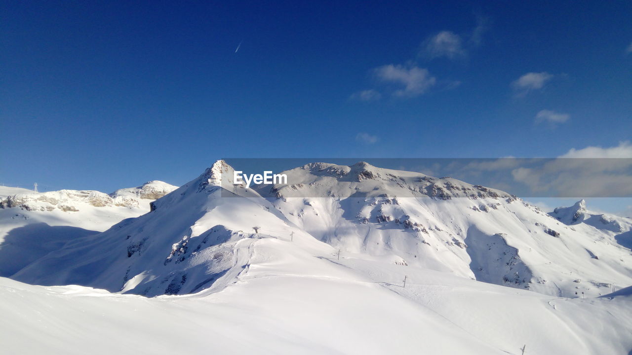 Scenic view of snowcapped mountains against blue sky